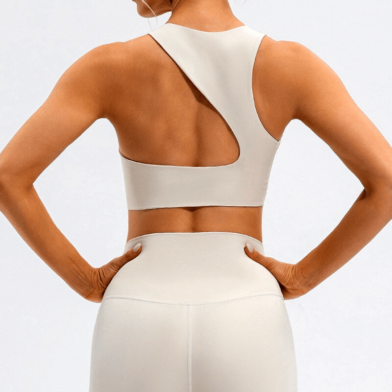 Open back women's sports bra in beige, showcasing flexible and breathable design, perfect for fitness and style.
